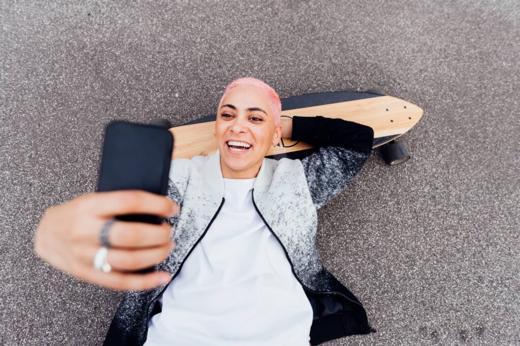 Woman with pink hair smiling on face time.