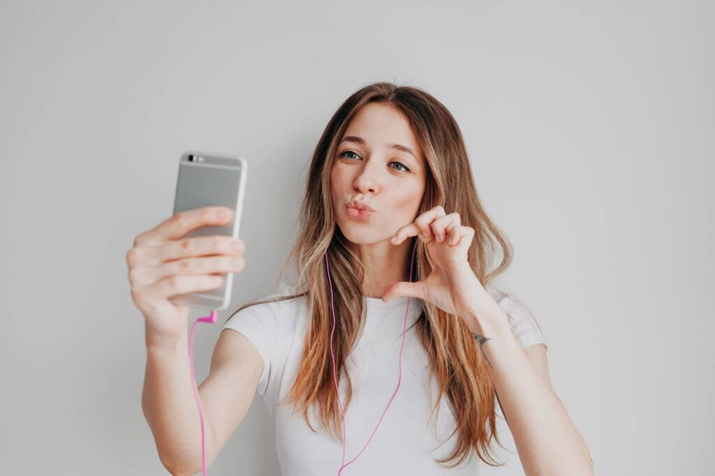 Pretty girl looking at phone and taking at selfie.