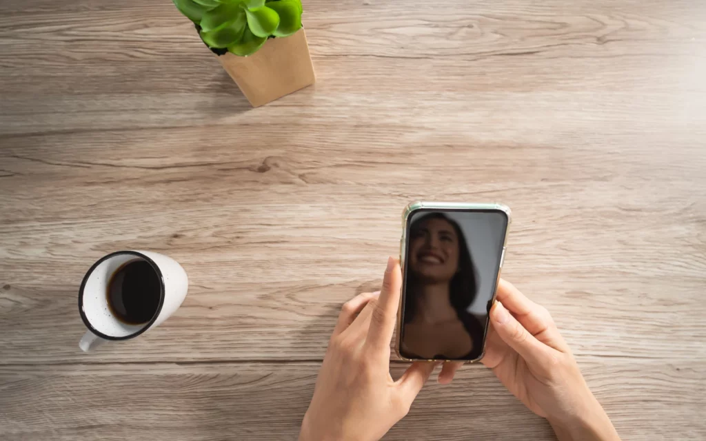 Happy girl using mobile smartphone while drinking coffee at home