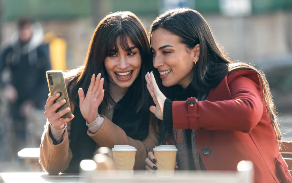 Two attractive friends enjoying coffee and creating Instagram video content