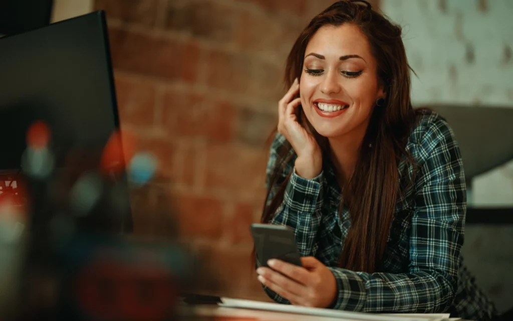 Young woman smiling while checking her Instagram