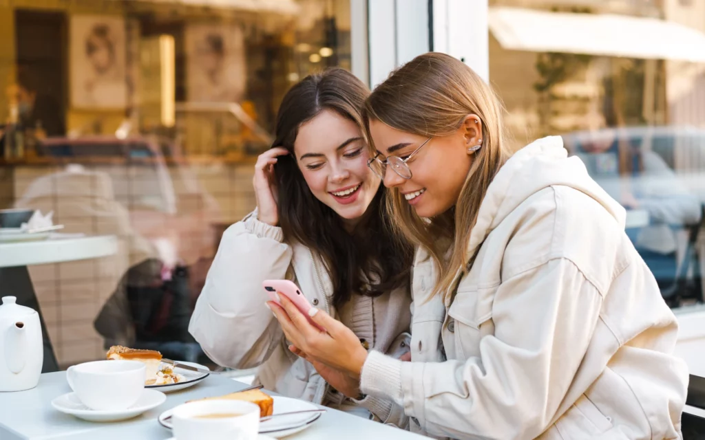 Two girls choosing the right hashtags for their social media post