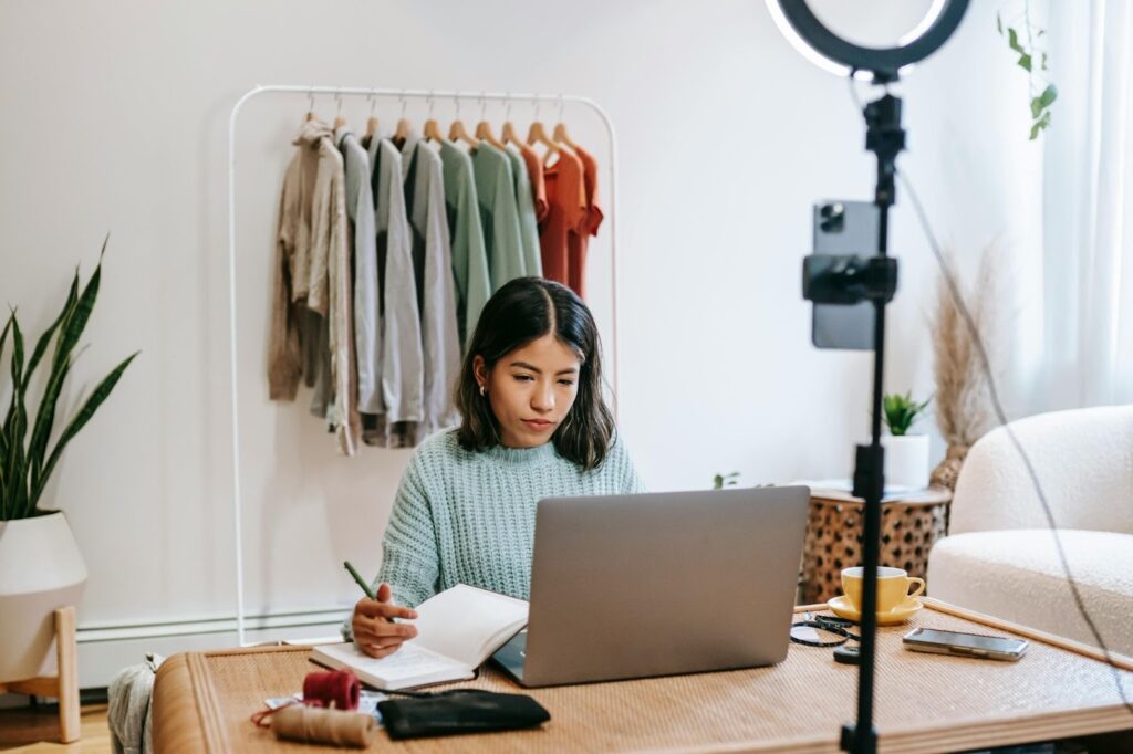 Woman working on her laptop and taking notes on her notebook