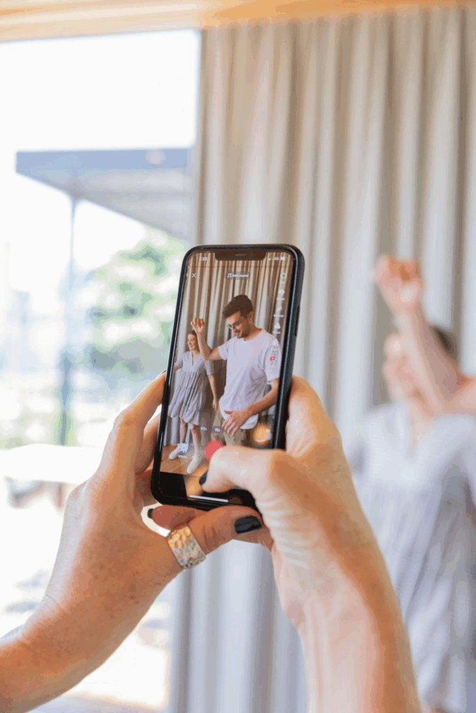 Woman recording two humans dancing with a phone.
