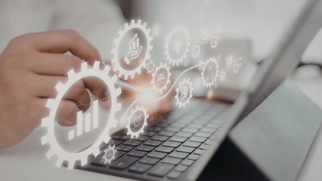 Hand using a tablet keyboard with translucent gear and analytics icons overlayed.