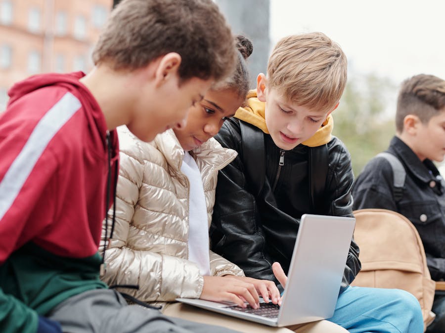 Group of teenagers studying together on a laptop outdoors, fostering collaboration.