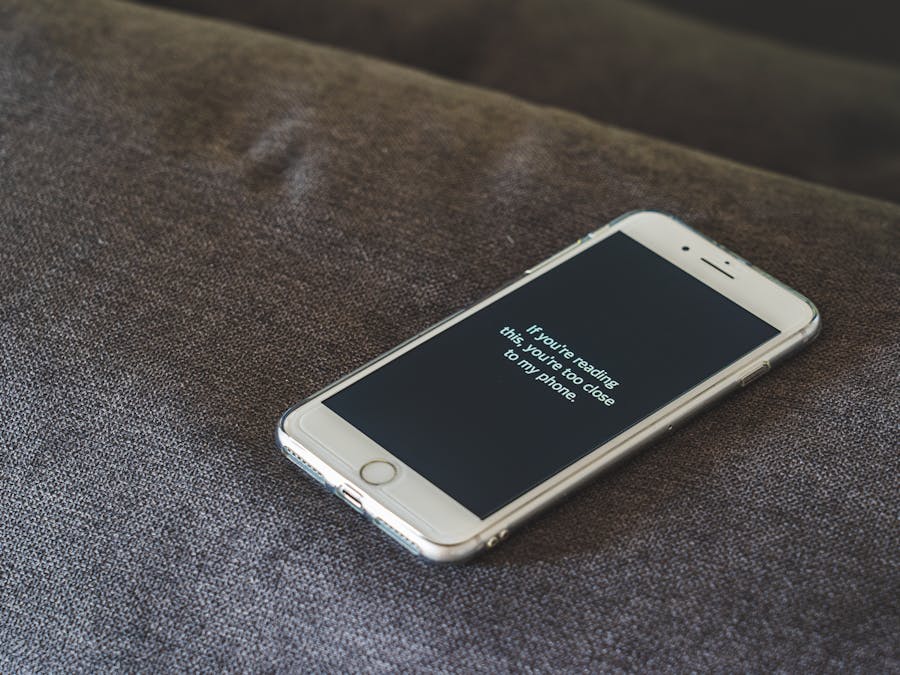A smartphone with a humorous lock screen message placed on a grey couch, emphasizing privacy.