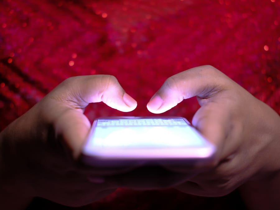 Hands typing on a smartphone with a glowing screen in low-light, highlighting technology and communication.