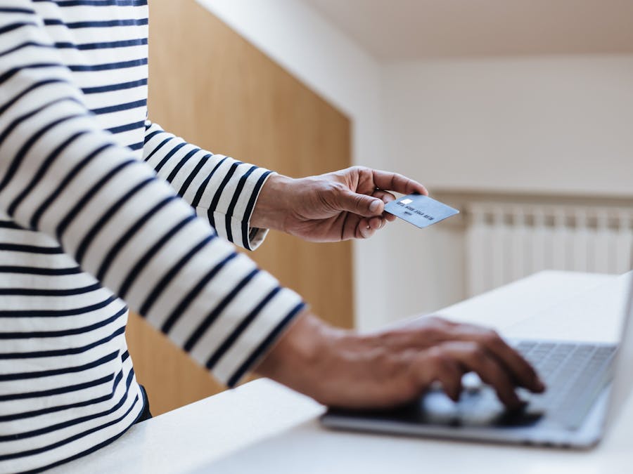 Person using a credit card for online shopping on a laptop indoors.