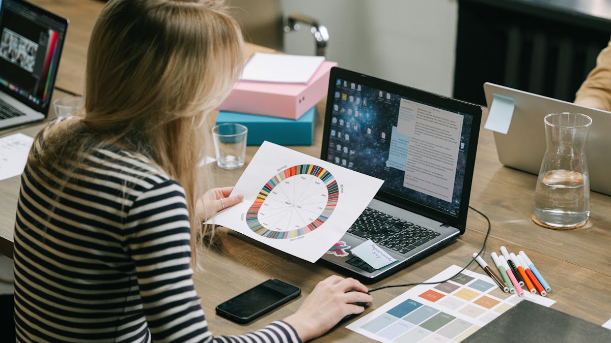 A woman studying a color wheel on a laptop during a work session in a modern office.