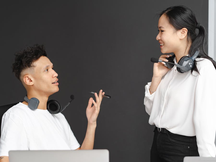 Two colleagues with headsets chat in a modern office setting, emphasizing teamwork and communication.