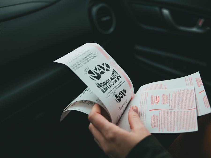 Close-up of hands holding Lotto Max papers inside a car, symbolizing luck and chance.