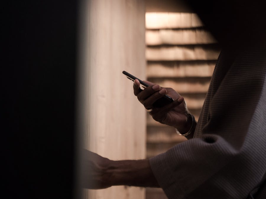 A person using a smartphone in a dimly lit indoor setting with moody lighting.