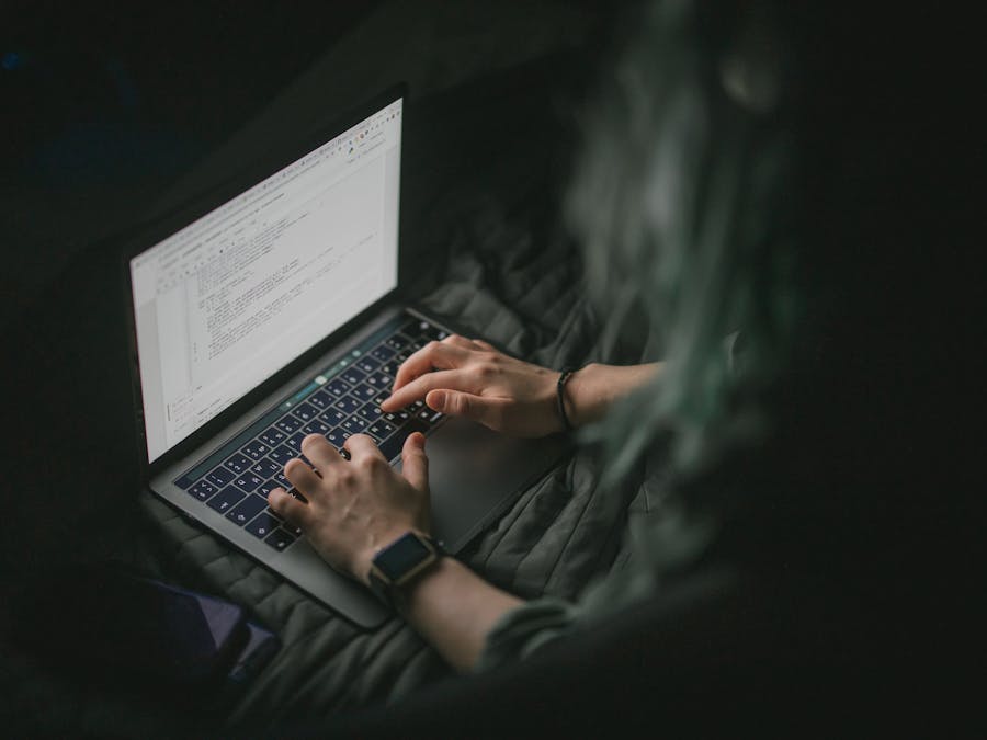 Close-up of hands typing on a laptop with code on screen, perfect for work from home and tech themes.