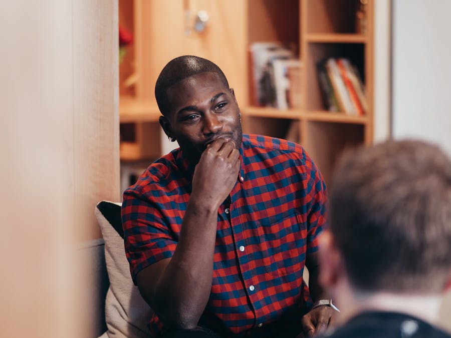 Two adults having a casual conversation indoors with a warm ambiance.