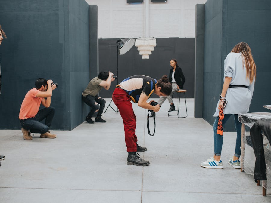 A group of photographers captures a model in a modern indoor studio setting.