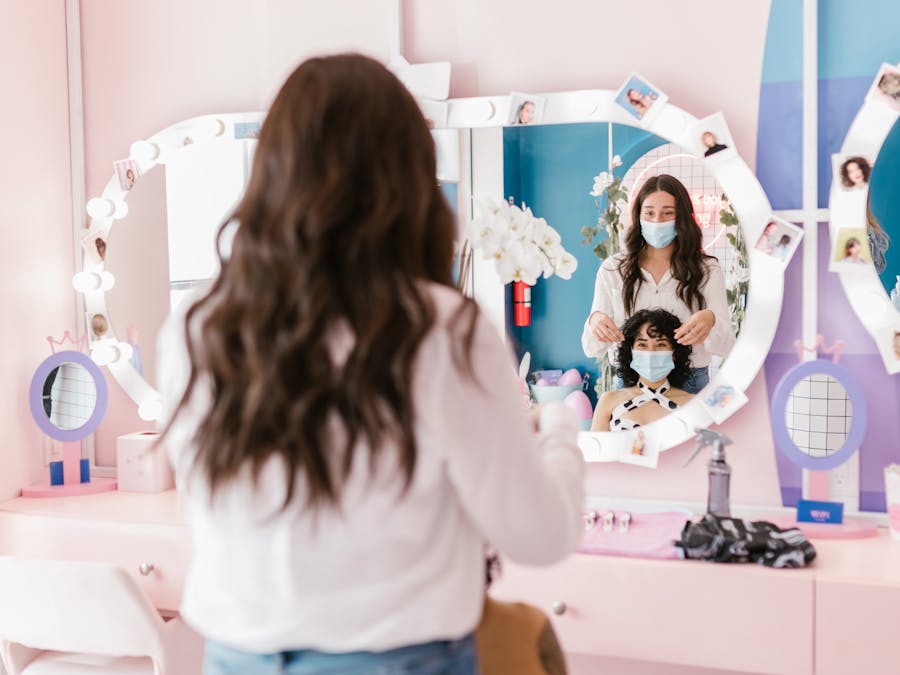 Hairdresser and client wearing masks in a modern salon, reflecting pandemic safety measures.
