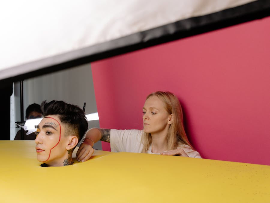 A behind-the-scenes look at a studio photoshoot featuring a model with unique makeup artistry and vibrant background.