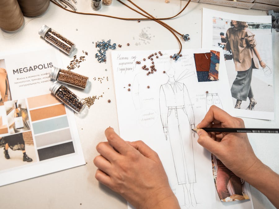 Fashion designer sketching in a workspace with materials and mood boards.