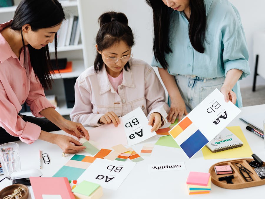 Three women engage in teamwork on a design project, sharing ideas and creativity.