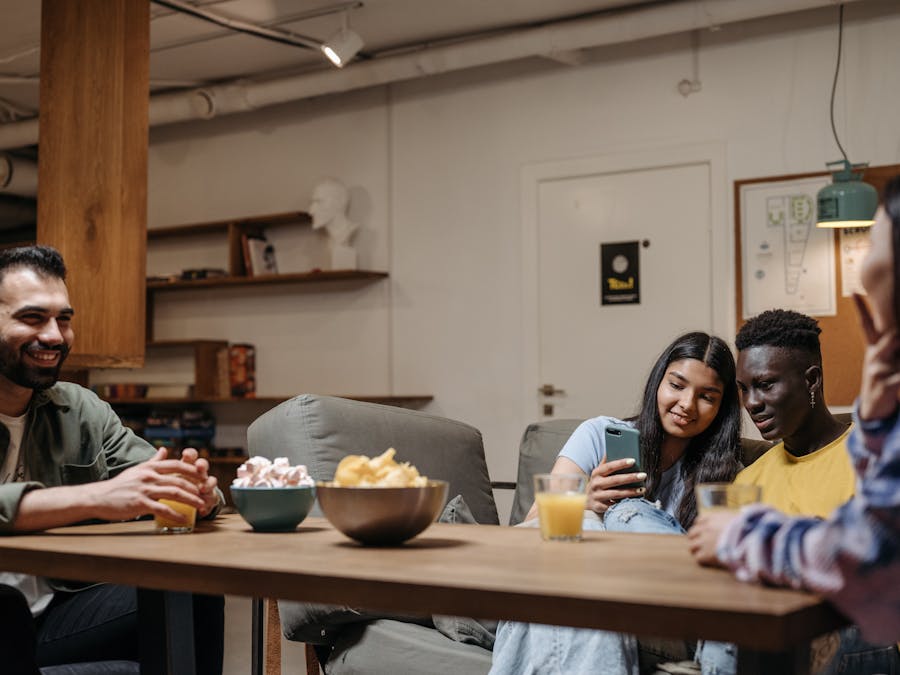 A diverse group of friends sitting together enjoying snacks and drinks indoors, capturing a moment of relaxation and bonding.