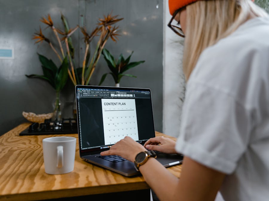 Focused woman typing on laptop while creating a content plan in a modern workspace.
