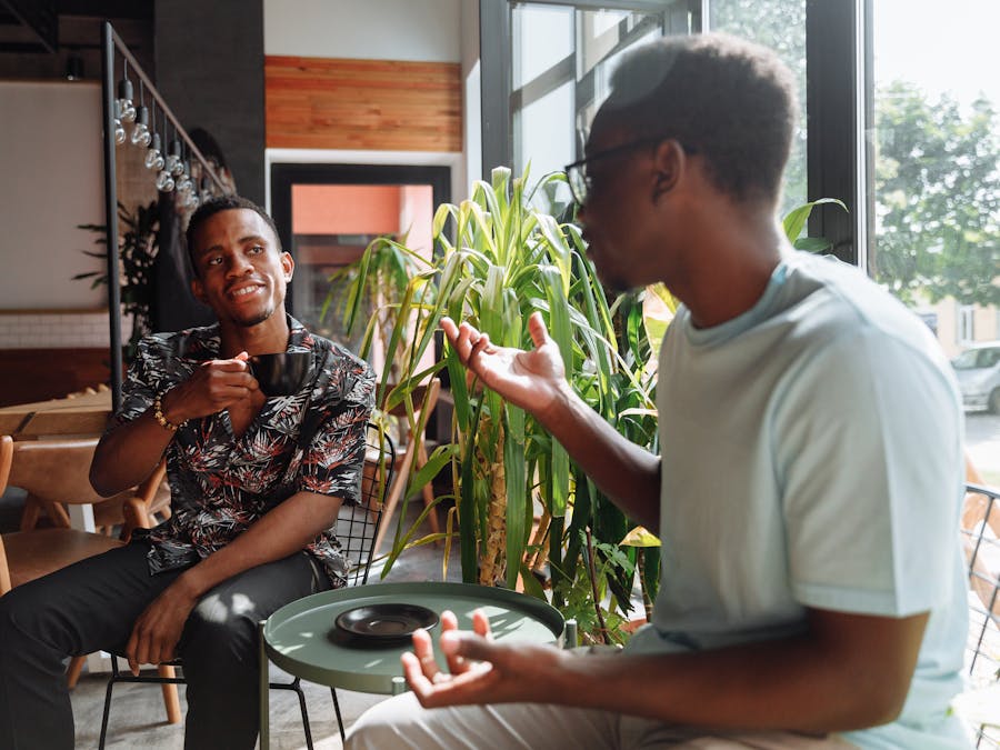 Two friends having a lively conversation over coffee in a cozy coffee shop setting.