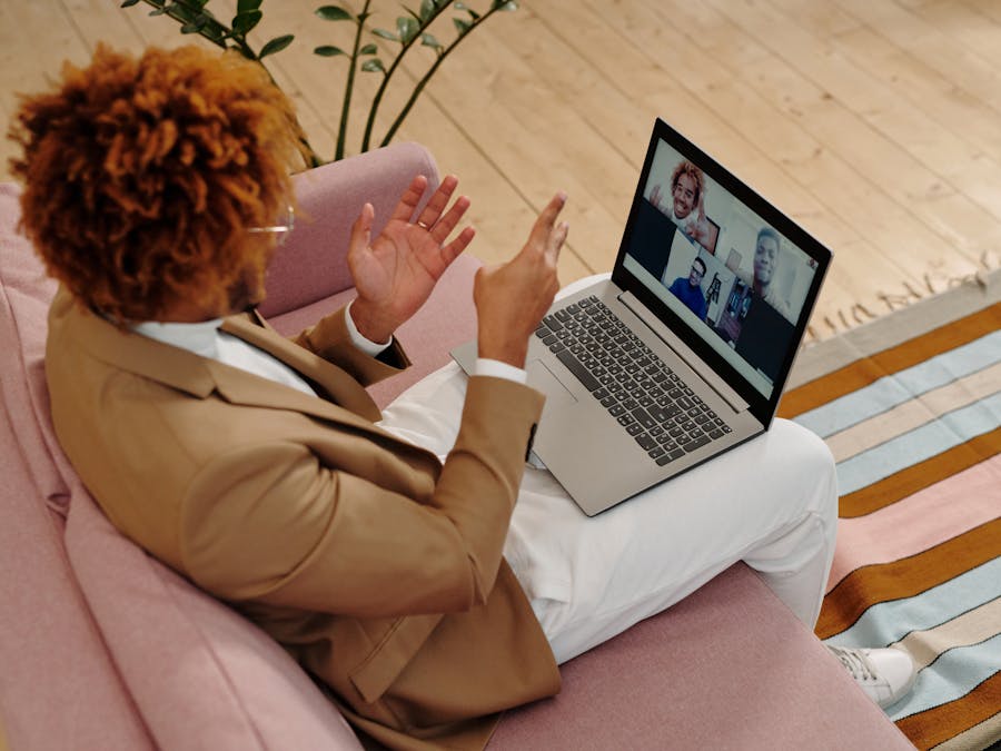 An adult man in a suit engages in a video call while sitting on a sofa indoors.