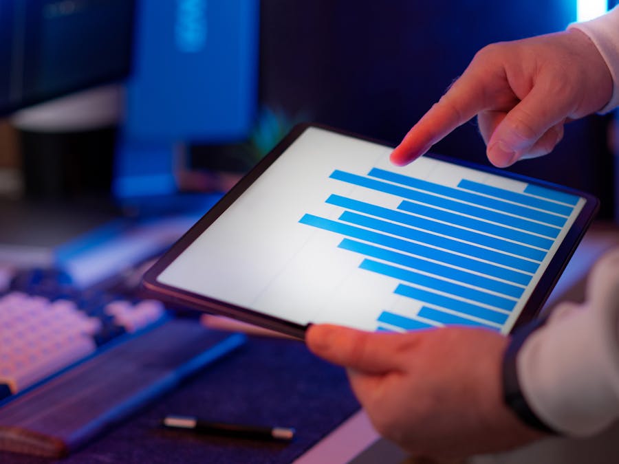 Business professional analyzing bar chart on tablet in office setting, highlighting data insights.