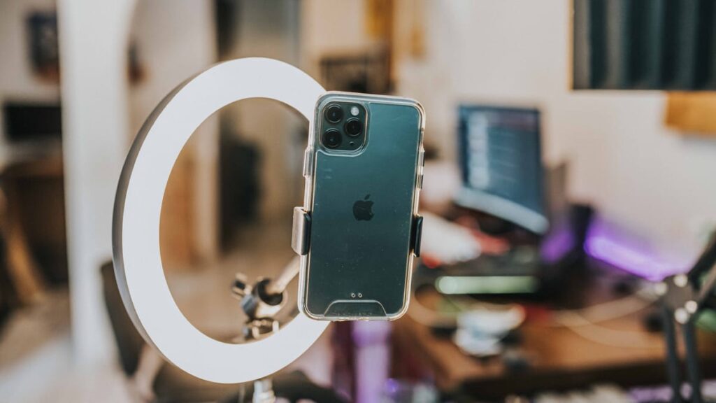 Smartphone mounted in ring light for content creation in modern workspace.