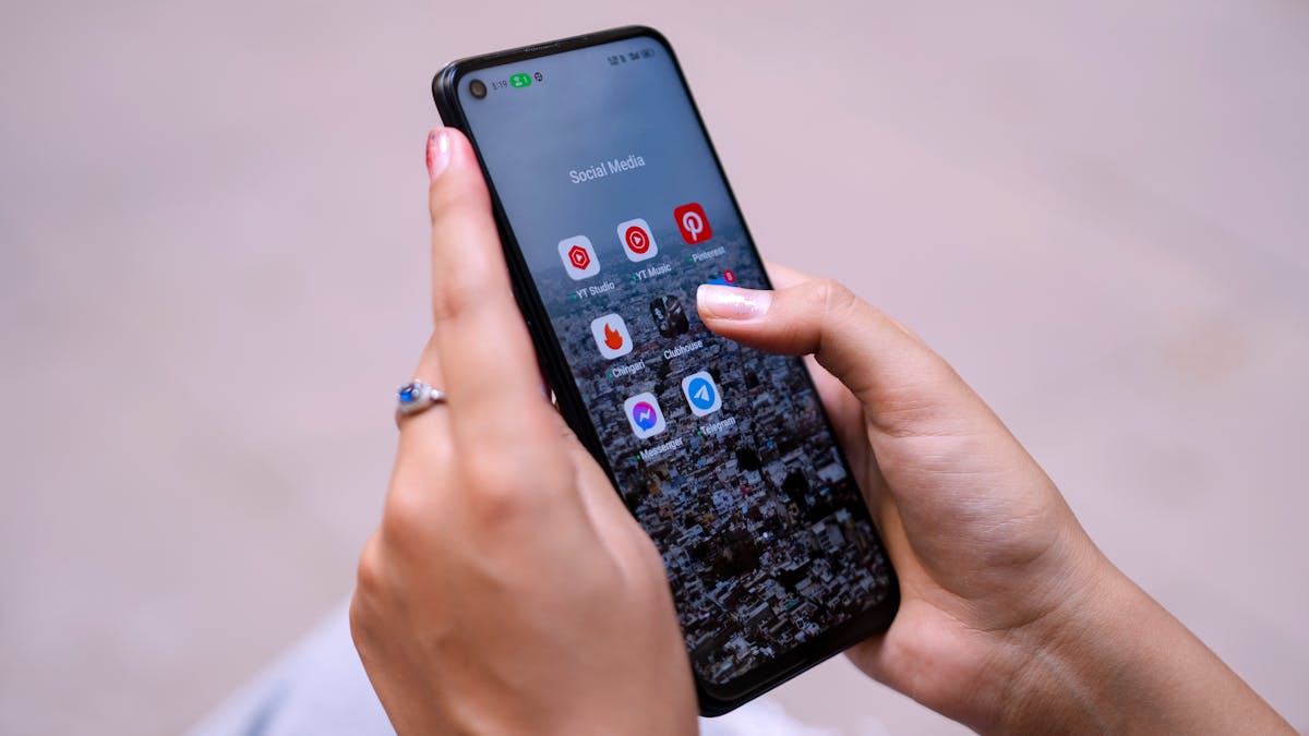 Close-up of hands holding a smartphone displaying social media apps, emphasizing digital connectivity.