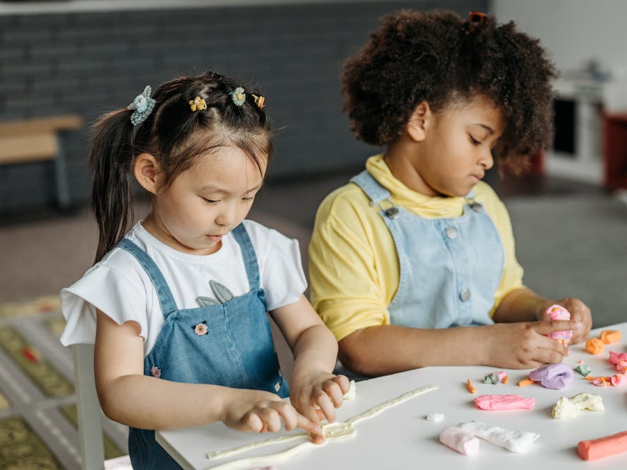 Two children playing with colorful clay indoors, fostering creativity and teamwork.