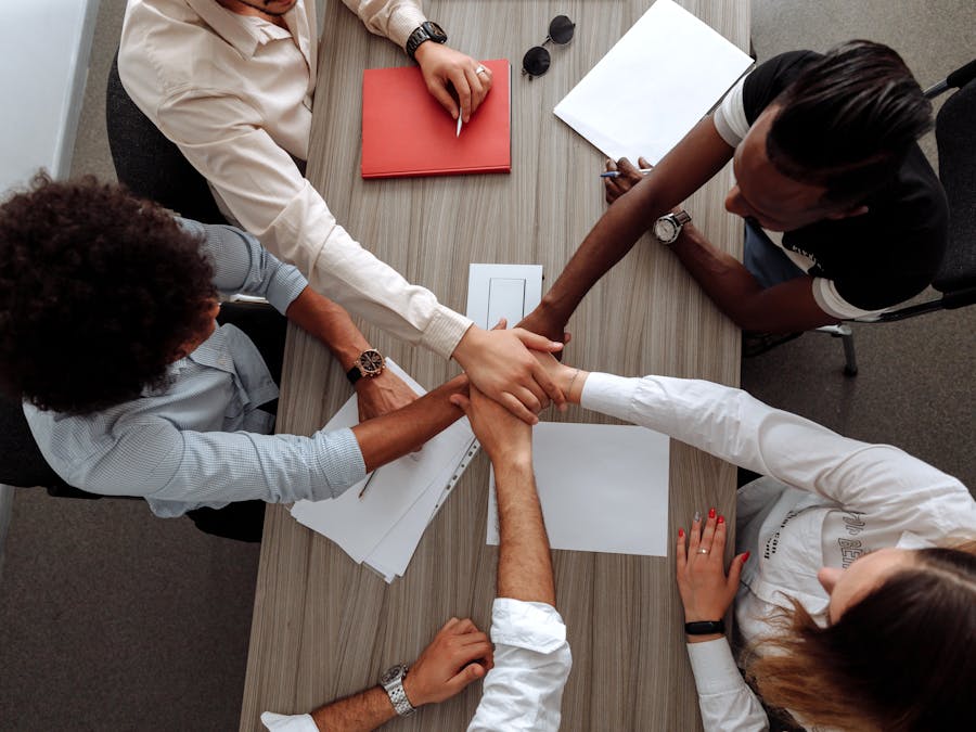 Overhead view of a diverse team placing hands together in a sign of unity during a meeting.