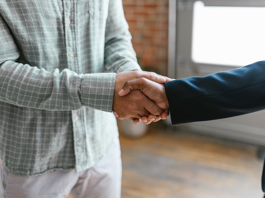 Close-up of two business professionals shaking hands in a modern office environment.