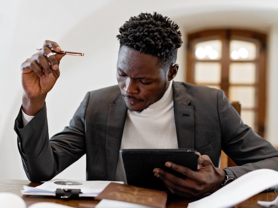 Confident businessman working on a tablet with documents in an office setting.