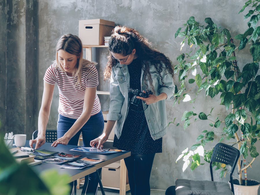 Two female designers examining photographs in a modern office space.