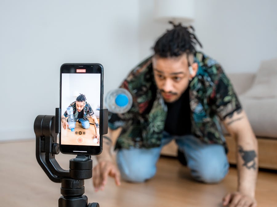 Man filming creative content with smartphone on gimbal indoors.