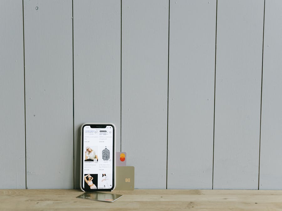 A smartphone displaying an ecommerce site with a credit card, set on a wooden surface, depicting online shopping.