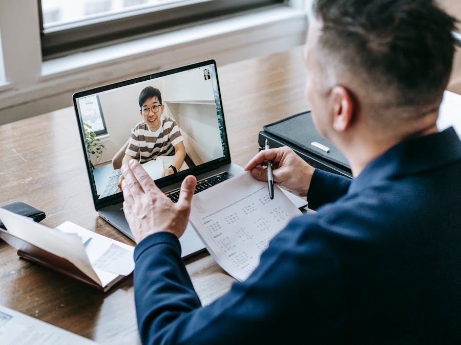A professional having a video conference on a laptop from a home office, engaging in online communication.
