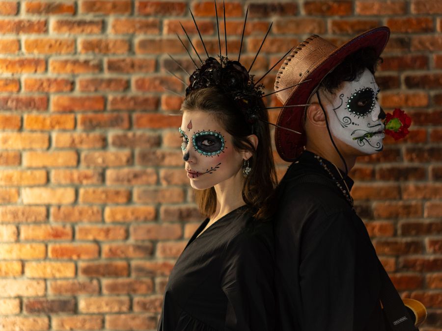 Elegant Dia de los Muertos themed portrait with intricate face paint and traditional outfits.