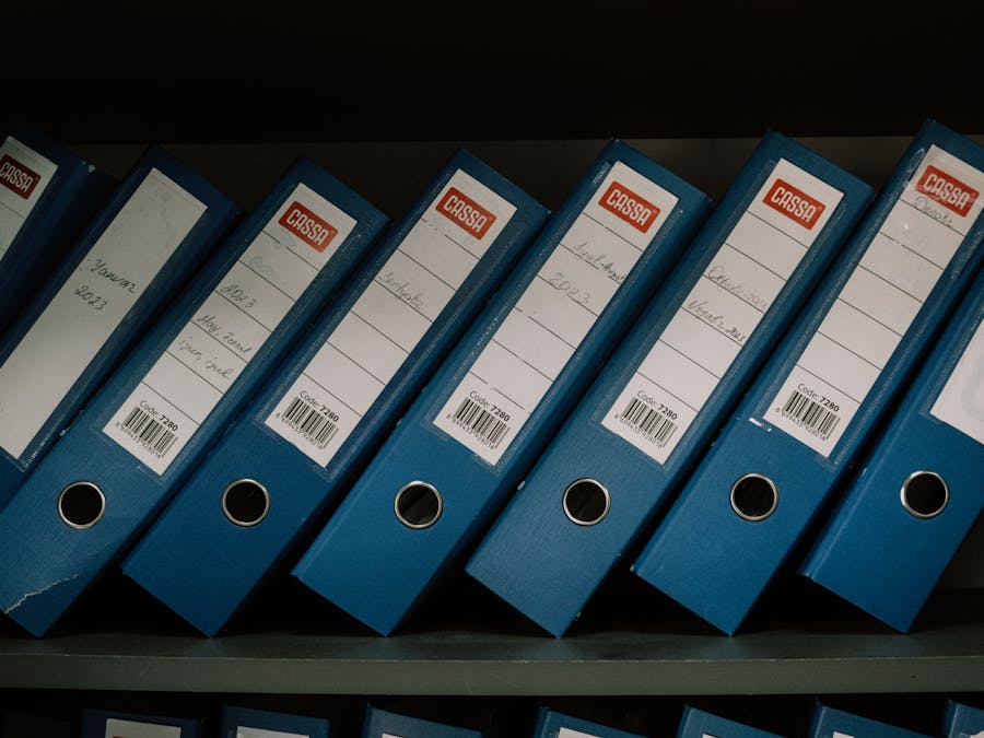 Neatly arranged blue office binders labeled with dates and names for organized storage.