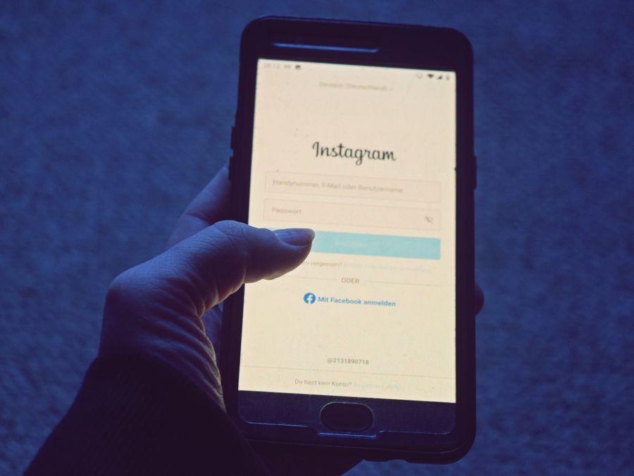 Close-up of a hand holding a smartphone displaying the Instagram login screen.