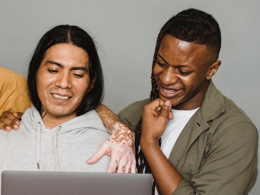 Delighted diverse colleagues smiling happily while working on remote project and surfing netbook together in studio