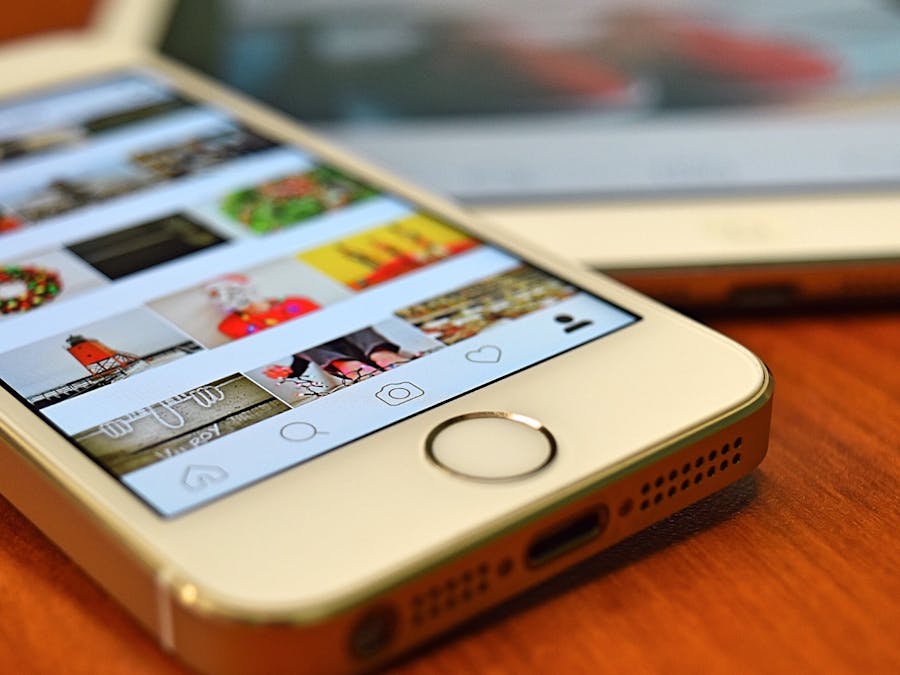 A close-up view of a smartphone displaying the Instagram app on a wooden surface.