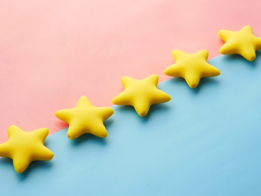 Yellow stars on pink and blue pastel background for rating or review concept.
