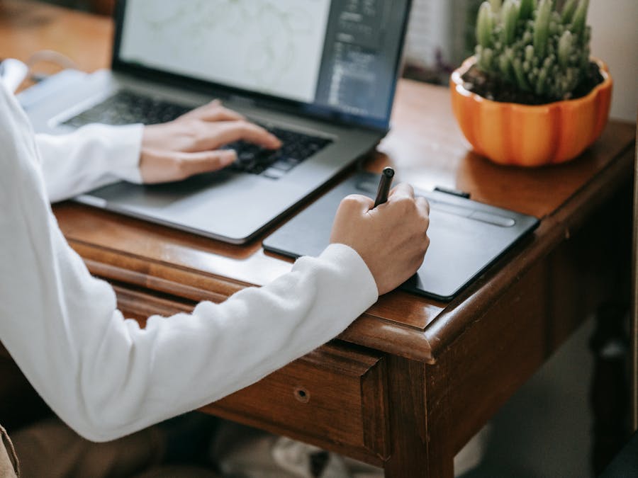 Close-up of designer working on graphics tablet with laptop, enhancing creativity and digital work.