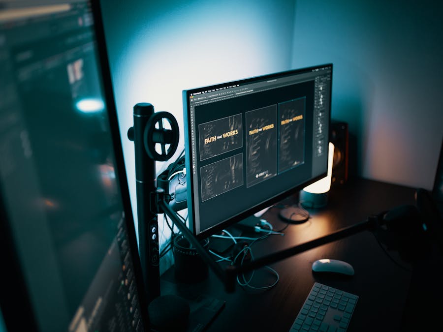 A stylish modern workspace with dual monitors displaying design software in a dimly lit room.