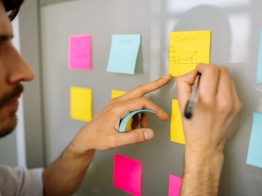 Focused businessman writing ideas on sticky notes for planning and organization.
