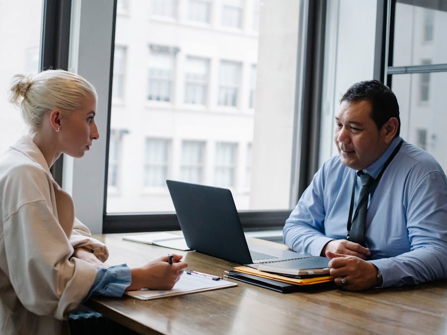 Ethnic boss asking question to female candidate filling information form on clipboard during hiring meeting