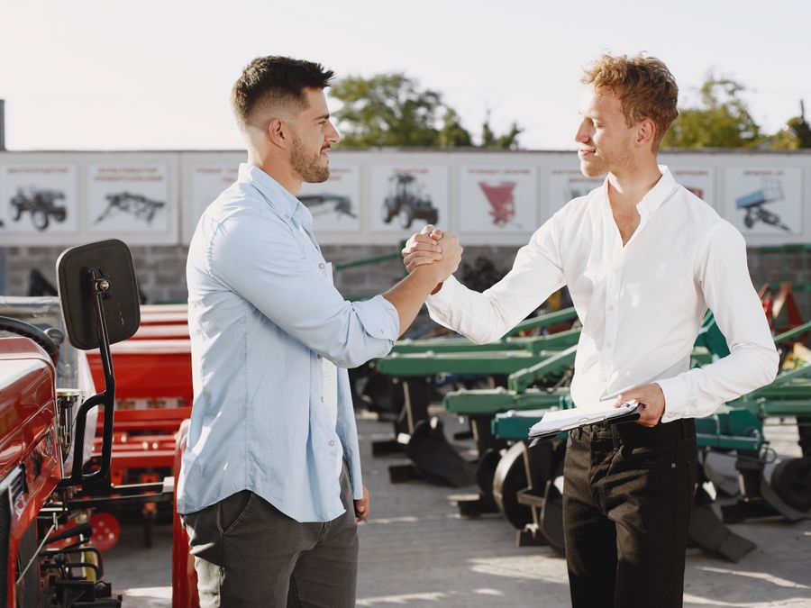 Two businessmen shaking hands outdoors, signaling a successful deal.